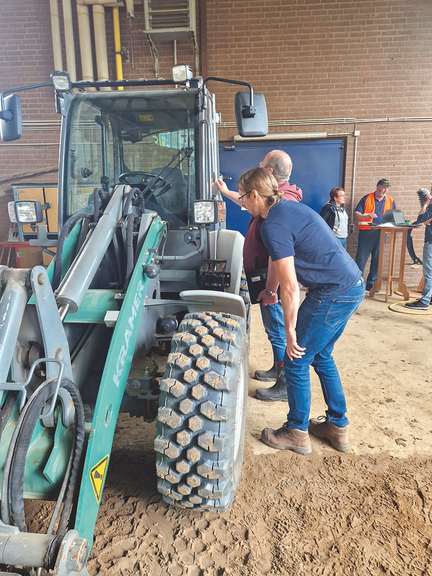 Vergrößerung des Bildes für Traktor steht in einer Halle, eine Frau schaut in die Fahrerkabine. Im Hintergrund Personen im Gespräch an Stehtischen. .