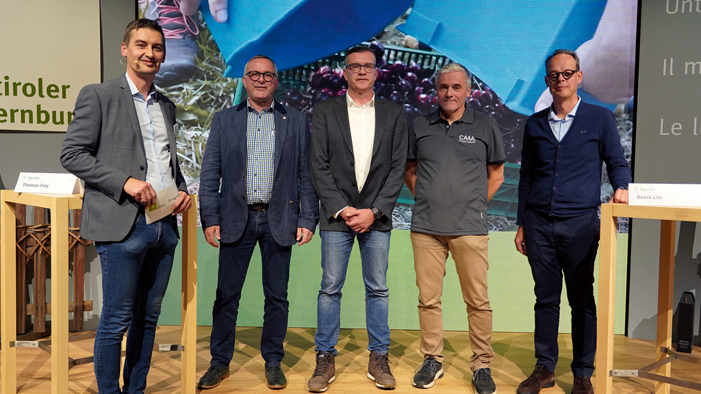 Vergrößerung des Bildes für Fünf Männer stehen auf einem Podium und schauen in die Kamera..
