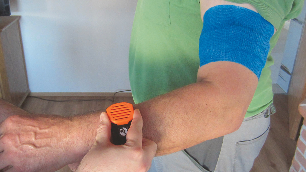 Vergrößerung des Bildes für An einem Handgelenk ist ein Armband angebracht mit einem Messgerät, in der Größe einer Armbanduhr. Am Oberarm ist ebenfalls ein Band angelegt..