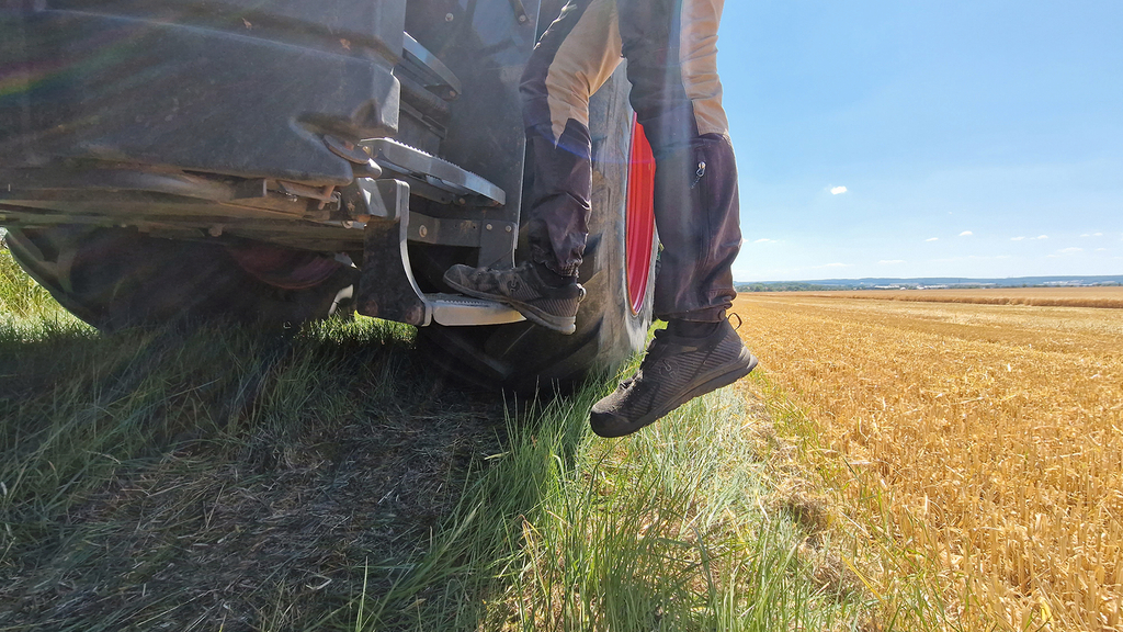 Vergrößerung des Bildes für Eine Person steigt von einem Schlepper ab, im Hintergrund ein Feld..