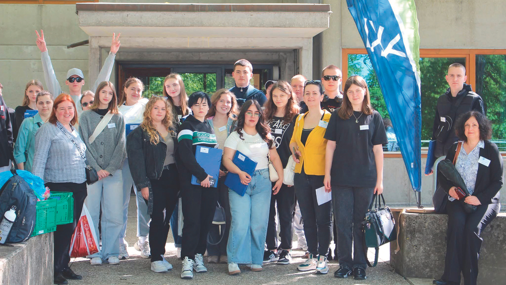 Vergrößerung des Bildes für Eine Gruppe junger Menschen steht vor einem Hauseingang und schauen in die Kamera.  .