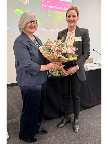 Vergrößerung des Bildes für Zwei Frauen stehen einander zugewandt. Die eine hält einen Blumenstrauß in den Händen. Beide schauen in die Kamera..