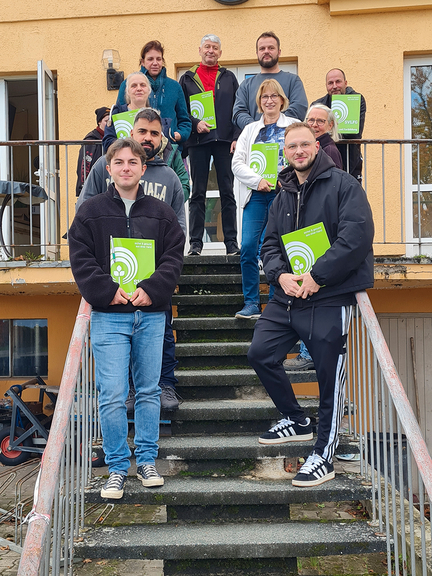Vergrößerung des Bildes für 10 Personen, die eine Urkunde in der Hand halten.