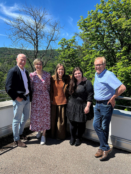 Vergrößerung des Bildes für Gruppenbild: Vier Personen stehen auf einer Terrasse und schauen lachend in die Kamera.