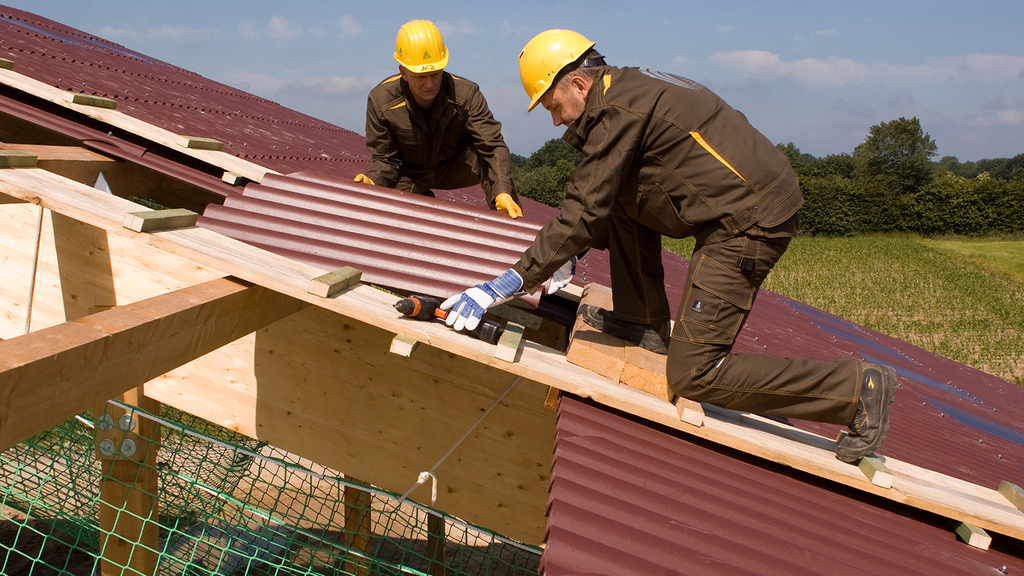 Vergrößerung des Bildes für Zwei Männer arbeitn auf einem Dach mit Fangnetzen als Sicherung.