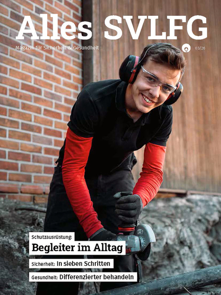 Vergrößerung des Bildes für Ein junger Mann mit Schutzbrille, Gehörschutz, Arbeitshandschuhen, Arbeitshose steht gebeugt über einem Werkstück und hält eine Flex. Dabei schaut er lächelnd auf und in die Kamera..