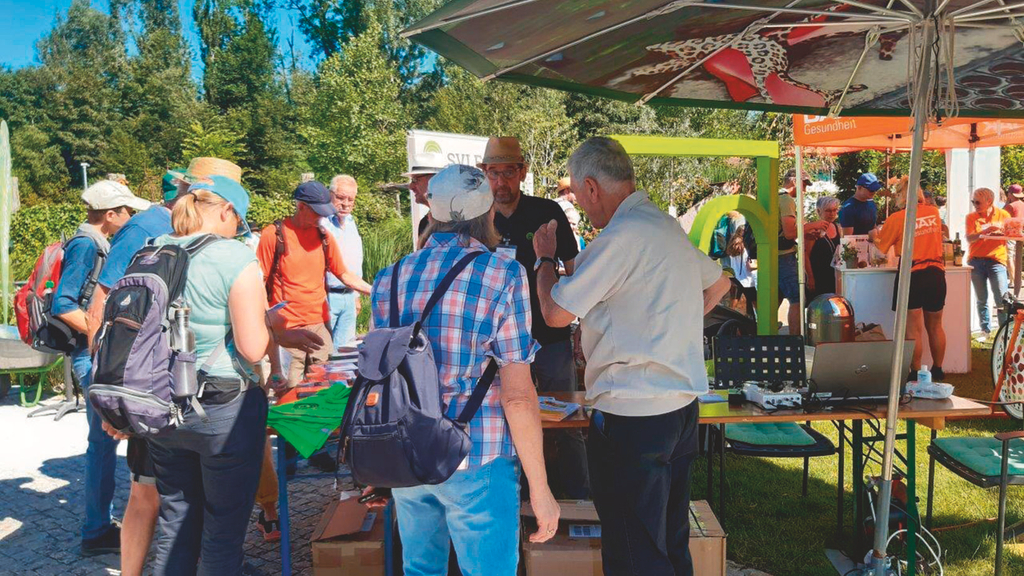 Vergrößerung des Bildes für Blick auf einen Infostand im Freien. Mehrere Besucher informieren sich und sind im Gespräch..